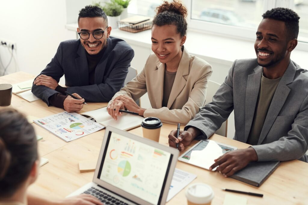 pexelsfauxels3184338 Beawareofmecom Three colleagues sitting at a meeting table smiling and discussing Mental Health in the Workplace