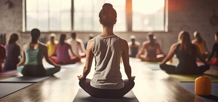 Adult practicing mindfulness meditation for ADHD mental health 10 Beawareofmecom A woman in a yoga studio meditating with hands in a prayer position surrounded by candles and soft lighting