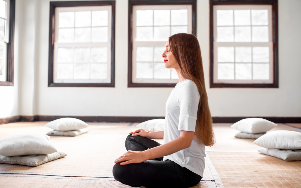 Adult practicing mindfulness meditation for ADHD mental health 4 Beawareofmecom A woman sitting in lotus position on the beach at sunset with the ocean waves in the background focusing on her breath