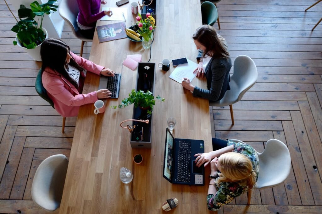 Tips for Managing Stress at Work 1 Beawareofmecom Three diverse women collaborating and discussing ideas while working on laptops highlighting teamwork and cooperation in a professional setting