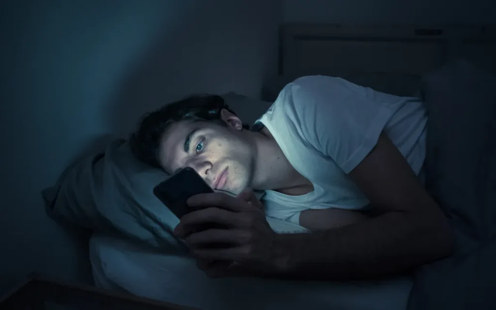 Person scrolling on phone late at night Beawareofmecom 10 Signs Youre Addicted to Social Media And How to Break Free