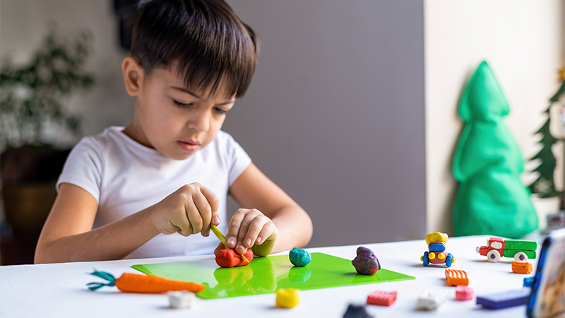 Cognitive Growth and Learning Beawareofmecom A young child focused on molding clay at a table illustrating how gentle parenting actually affects kids by nurturing creativity focus and cognitive development