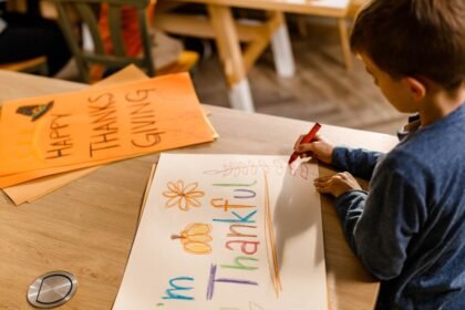 A young boy colors a Thanksgiving-themed poster at a table, highlighting how gentle parenting actually affects kids by encouraging creativity, gratitude, and emotional expression in a calm environment.