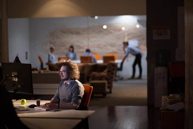 man working on computer in dark office Beawareofmecom Supportive Work Environment